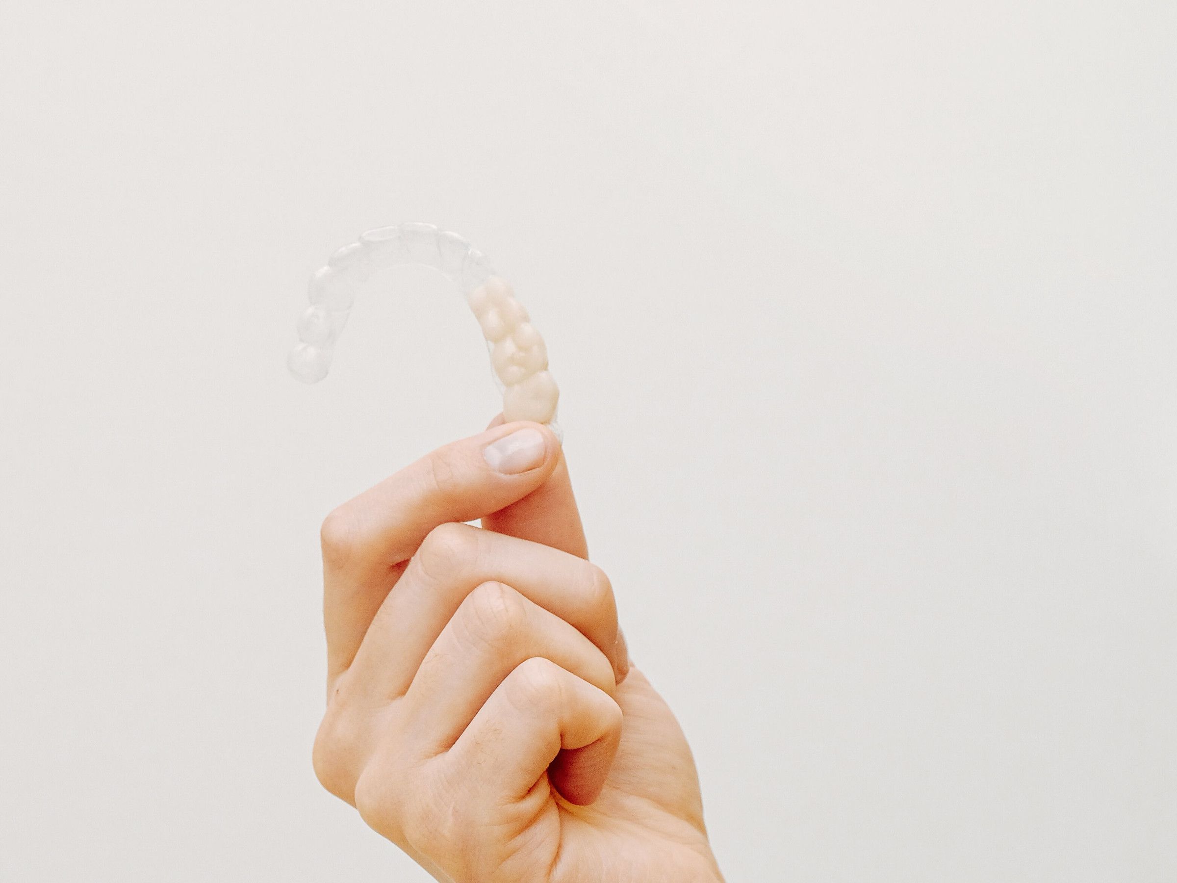 A clear aligner held between two fingers