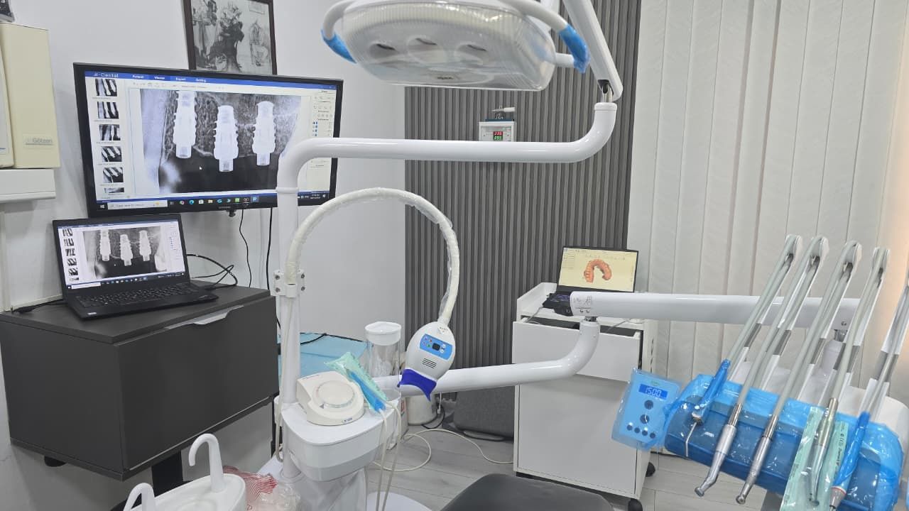 The treatment room, with the dental unit and implant radiographs on the monitor and laptop